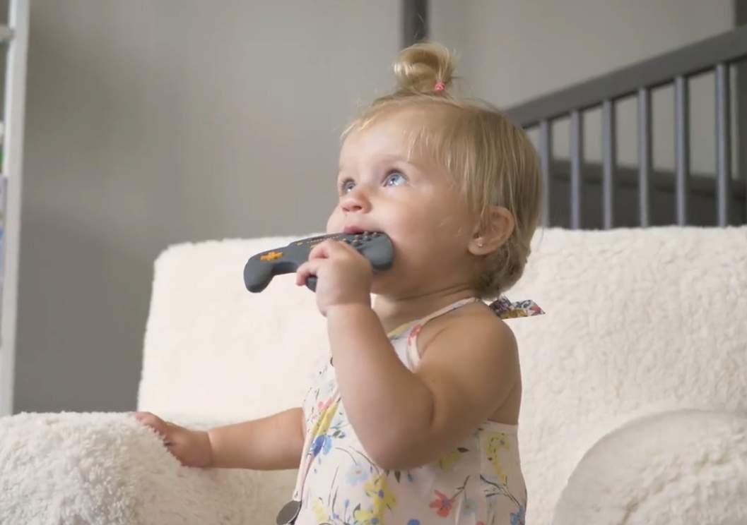 A baby chewing on BabyGlitch gaming remote toy